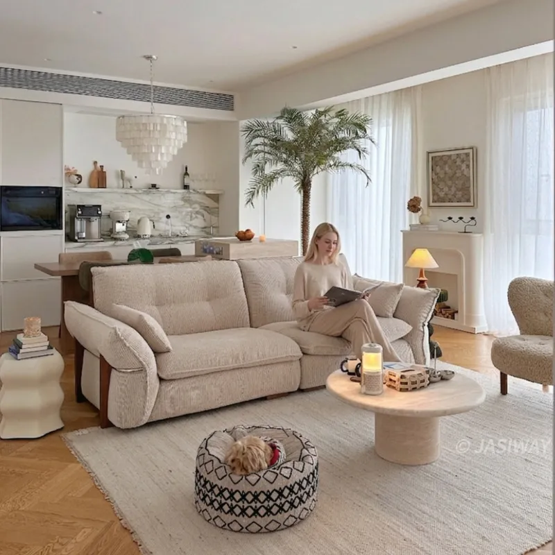 A modern open-concept living space features a plush natural fiber upholstered sofa and textured rug, creating a serene, inviting atmosphere for relaxation.