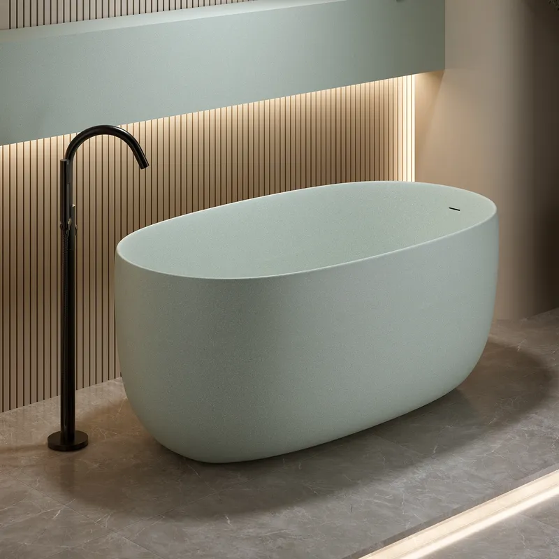 A minimalist freestanding ceramic bathtub in a soft sage hue anchors this contemporary bathroom design, complemented by dark metallic fixtures, subtle fluted wood paneling, and large format natural stone floor tiles.
