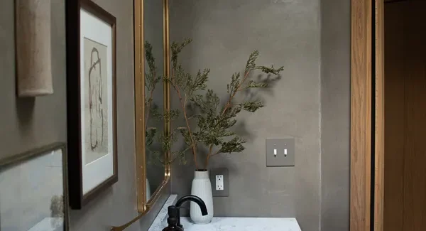 A chic powder room features a smooth clay-based wall finish, a luxurious marble vanity, and a warm wooden cabinet, creating a sophisticated and textured modern interior.