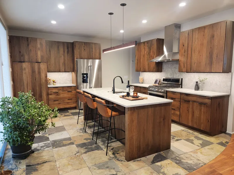This warm, modern kitchen design features rich stained wood cabinetry, white quartz countertops, and a striking slate tile floor with a large center island.